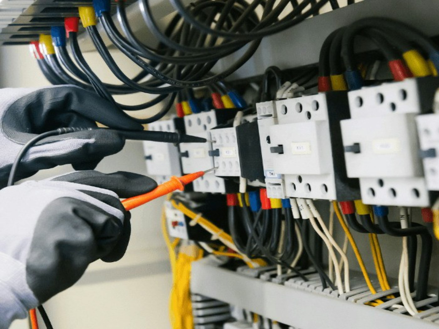 Electrician testing electrical panel equipment with a multimeter